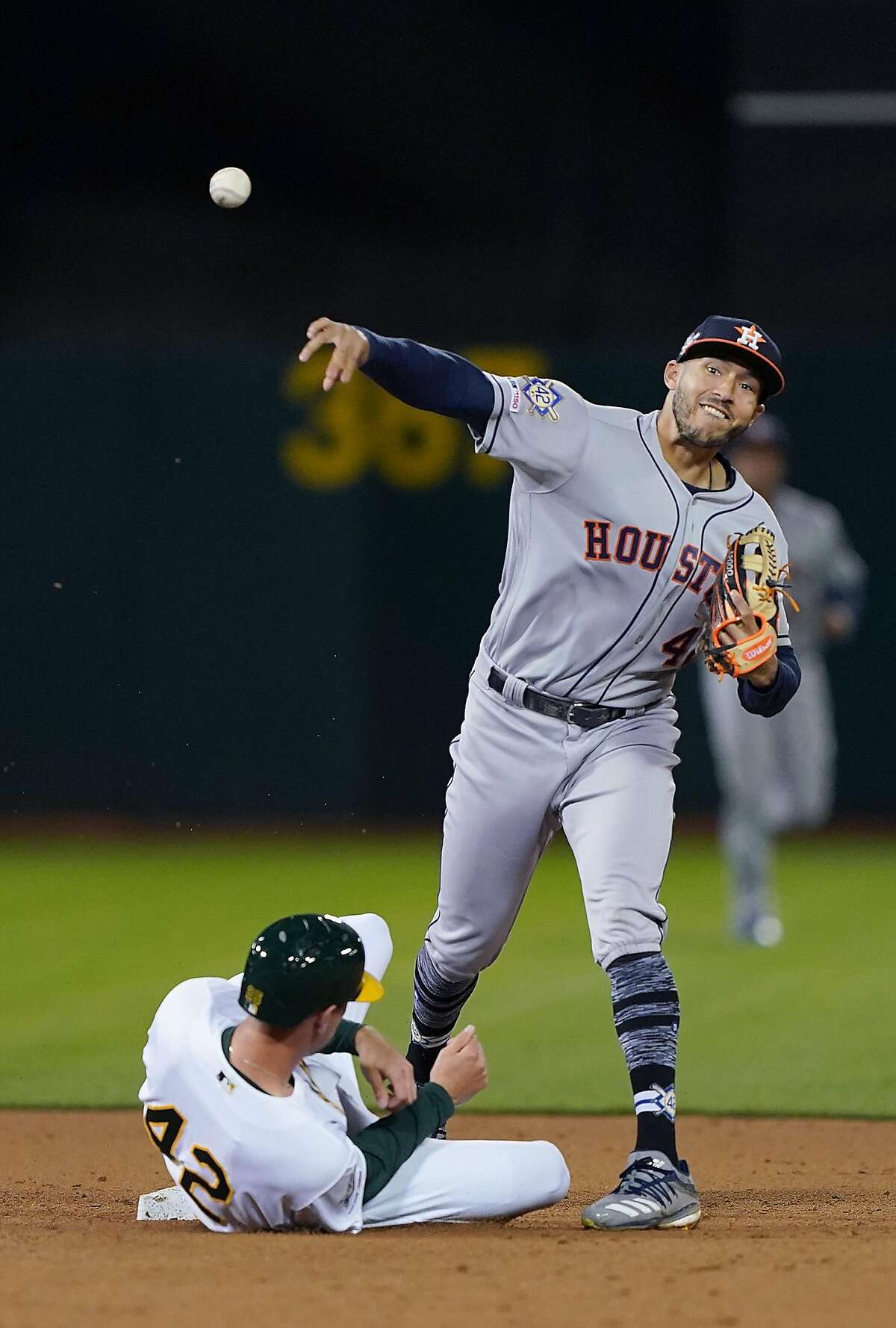OAKLAND, CA - APRIL 16: Carlos Correa #1 of the Houston Astros completes the double-play throwing over the top of Stephen Piscotty #25 of the Oakland Athletics in the bottom of the fifth inning of a Major League Baseball game at Oakland-Alameda County Coliseum on April 16, 2019 in Oakland, California. All uniformed players and coaches are wearing number 42 in honor of Jackie Robinson Day. (Photo by Thearon W. Henderson/Getty Images)