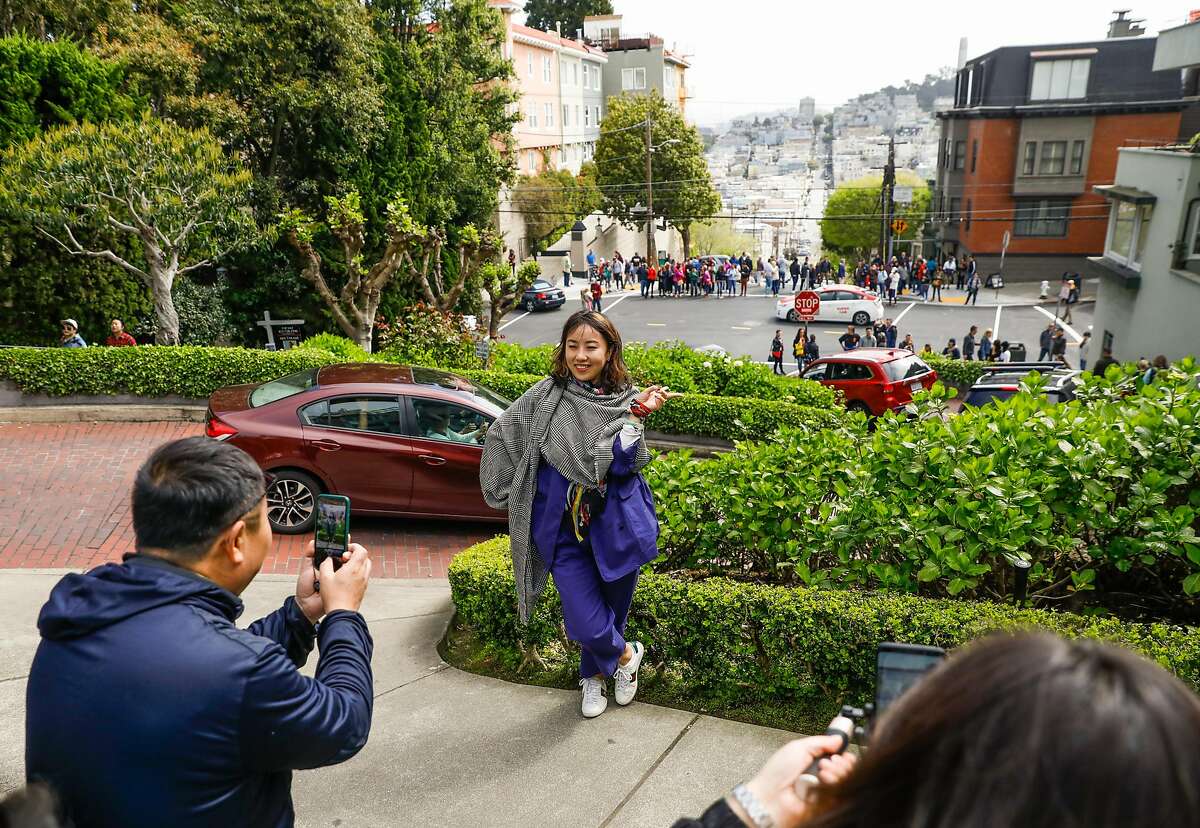 Ada Xu (center), who is visitng from China, gets photographed while visiting Lombard Street in San Francisco, California, on Sunday, April 14, 2019.