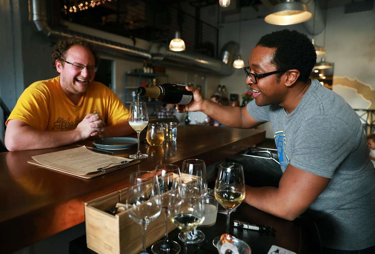 Andy Copeland (left) watches Chris Gaither pour a glass of champagne at Ungrafted, a wine bar located at 2419 3rd St., in San Francisco, Calif., on Wednesday, April 10, 2019. Gaither and his wife Rebecca Fineman are co-owners of the new establishment.