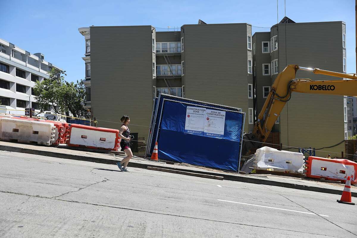 A person jogging runs past a construction site on Gough Street near Eddy Street on Thursday, April 18, 2019 in San Francisco, Calif.