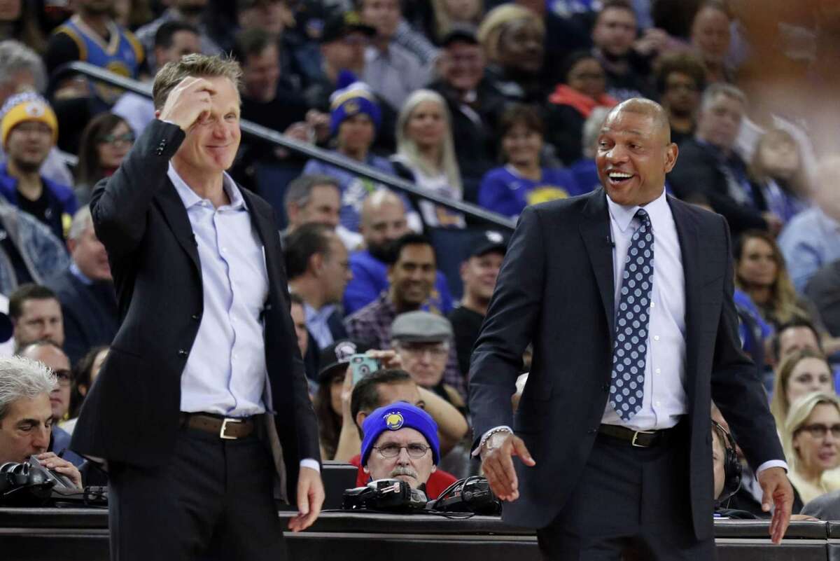 Golden State Warriors' head coach Steve Kerr and Los Angeles Clippers' head coach Doc Rivers share a light moment in 2nd quarter during NBA game at Oracle Arena in Oakland, Calif., on Thursday, February 22, 2018.
