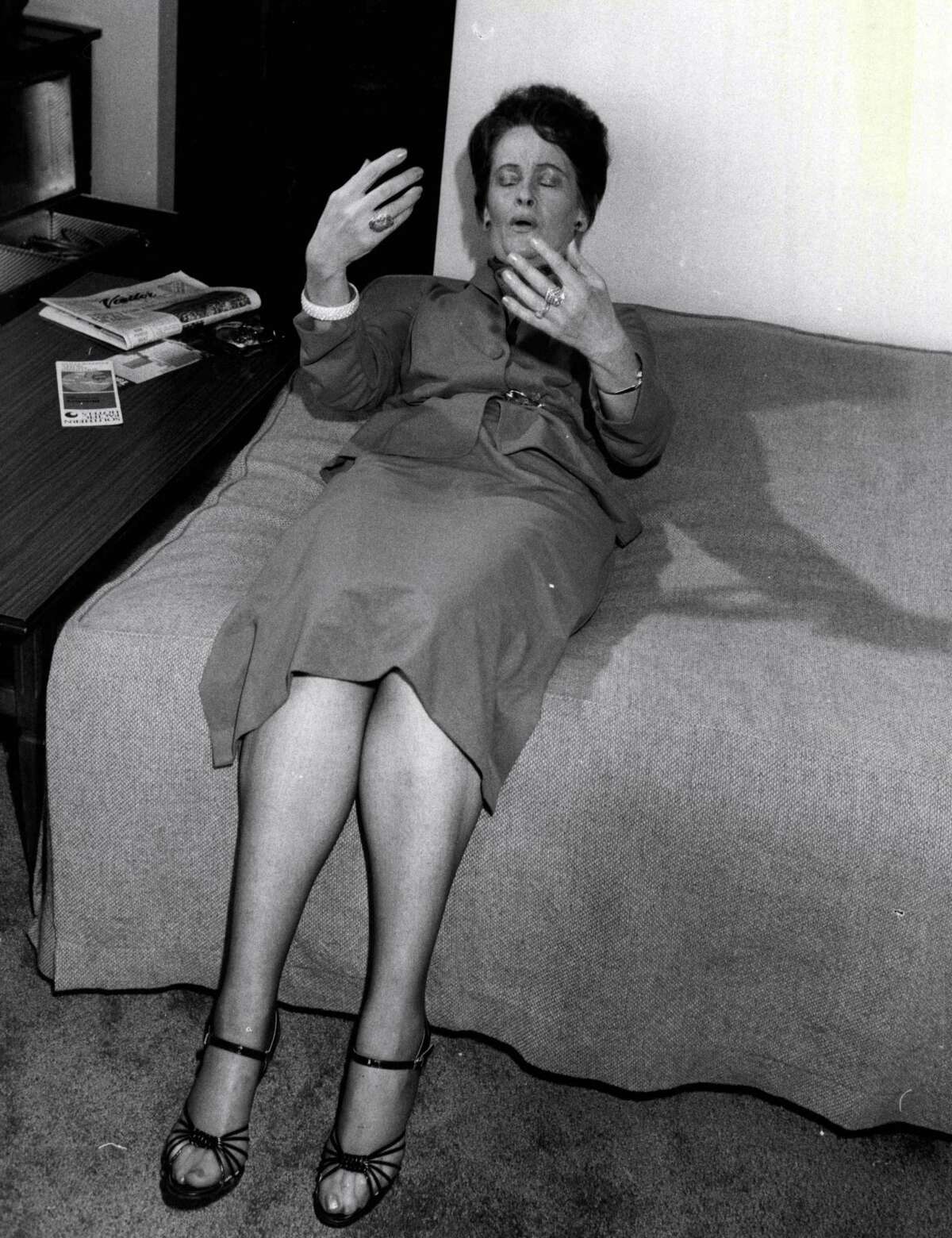 American ghost hunter, Mrs. Lorraine Warren shows how she lay back on a bed in the home of Mrs. Wendy Evans of Gladesville, and that she felt vibrations.