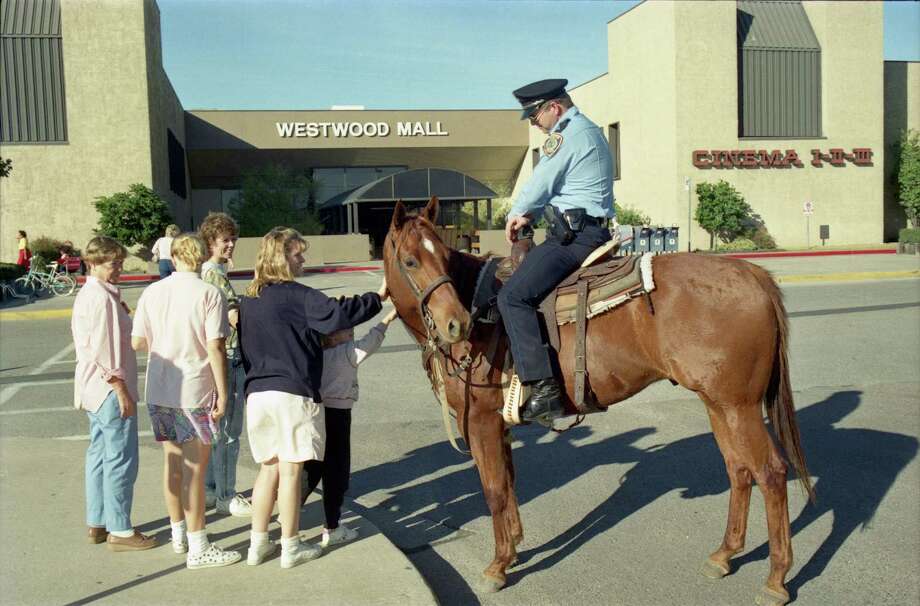 In this photo from 1988, an off-duty Houston police patrolman and his personal horse, Mike, meet with shoppers as he patrols a Westwood Mall parking lot. (Staff file photo) / Houston Chronicle