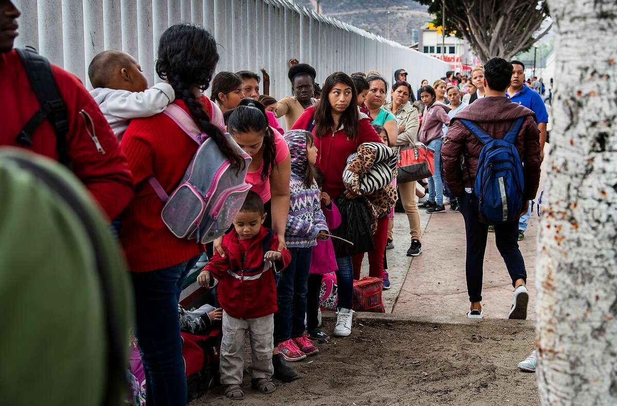 Asylum-seeking immigrants line up at a border fence in Tijuana, Mexico on June 20, 2018.