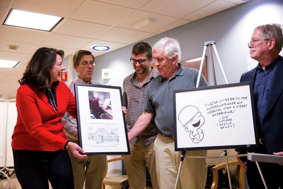 Brian Walker, son of the late Mort Walker, receives a framed image of one of his father’s final days at Stamford Hospital, accompanied by a comic strip by Bill Janocha in tribute to Mort Walker’s life. Mort Walker was the creator and illustrator of the “Beetle Bailey” comic strip, which began in the 1950s and is still in production. Stamford Health President and CEO Kathleen Silard is handing over the framed picture. An image of Mort Walker’s final Beetle Bailey drawing will hang outside of the hospital’s rehabilitation center. Also pictured, from left to right, are Janocha, Brian Walker’s son David and Mort Walker’s son Greg Walker. Photo: Contributed Photo / Minush Krasniqi / Stamford Advocate Contributed