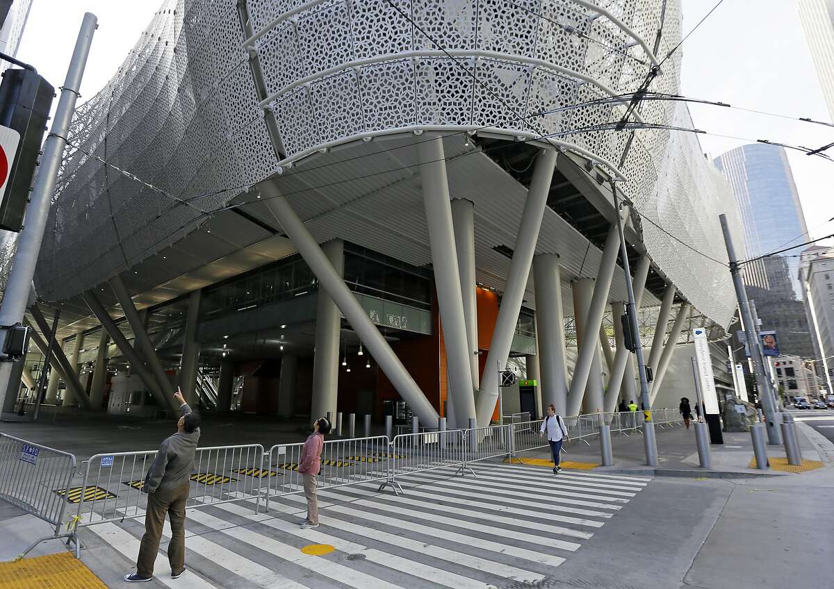 FILE - In this Sept. 27, 2018, file photo, people stop to look at the closed Salesforce Transit Center in San Francisco. Officials say the $2 billion transit terminal in San Francisco that shut down six weeks after opening last year is on track to be repaired by June, 2019, but there is no firm re-opening date. The Transbay Joint Powers Authority operates the Salesforce Transit Center, which opened Aug. 12, 2018 to great fanfare. They closed it the following month after finding two cracked beams. (AP Photo/Eric Risberg, File)