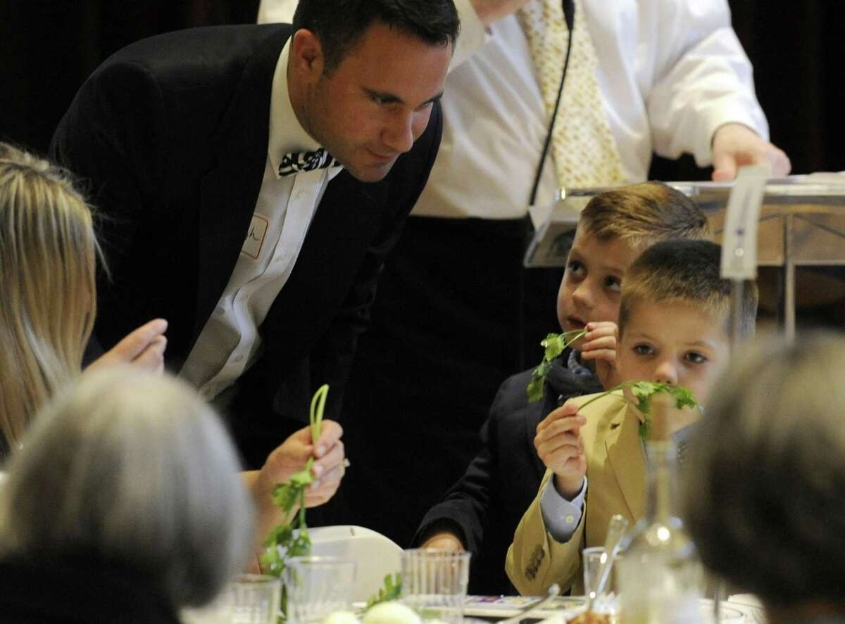 Rev. Daniel Haugh, Associate Pastor of Round Hill Community Church, watches as his sons Jack and Blake smell and taste parsley dipped in saltwater during an Interfaith Passover Seder at Temple Sholom on Friday in Greenwich. Parsley is a symbol of spring, and saltwater signifies tears the Israelites slaves shed. The Passover Seder is a Jewish ritual feast that marks the beginning of the Jewish holiday of Passover.