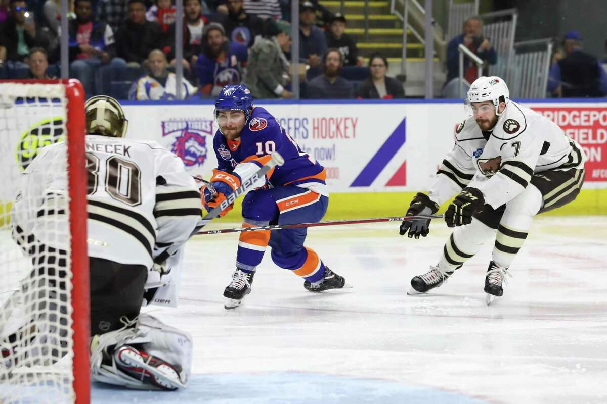 Ryan Bourque (10) of the Bridgeport Sound Tigers takes a shot on net while Connor Hobbs (7) of Hershey looks to defend and Vitek Venecek (30) of Hershey looks to make the save during game two of the first round of the AHL Calder Cup Playoffs between the Bridgeport Sound Tigers and the Hershey Bears on April 20, 2019 at Webster Bank Arena in Bridgeport, CT.