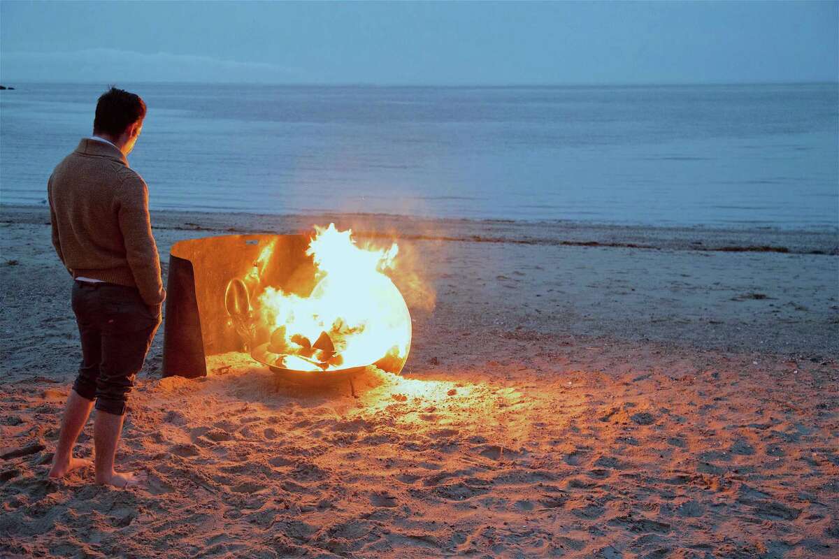 The Rev. Thomas Burke, associate pastor at Norfield Congregational Church in Weston, warms up by the fire at the Easter morning Sunrise Service at Compo Beach.
