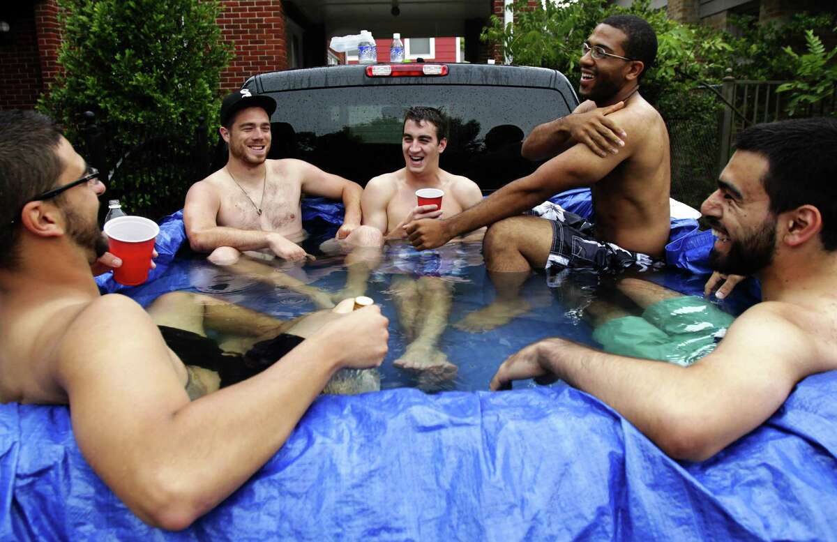 (From left to right) Nick Lunig, Cory Swaim, Will Langevin, Mike Haynes-Pitts and Rob Granados enjoy the summer time as they sit in in the back of Lunig's truck on Pecore Street while it rained Monday, June 6, 2011, in Houston. While his original idea was to beat the heat, Lunig put a tarp in the back of his truck and filled it water. "It's a redneck hot tub," Lunig said. "Although weather conditions aren't ideal, the water is so warm and the company is so good." Lunig said. ( Cody Duty / Houston Chronicle )