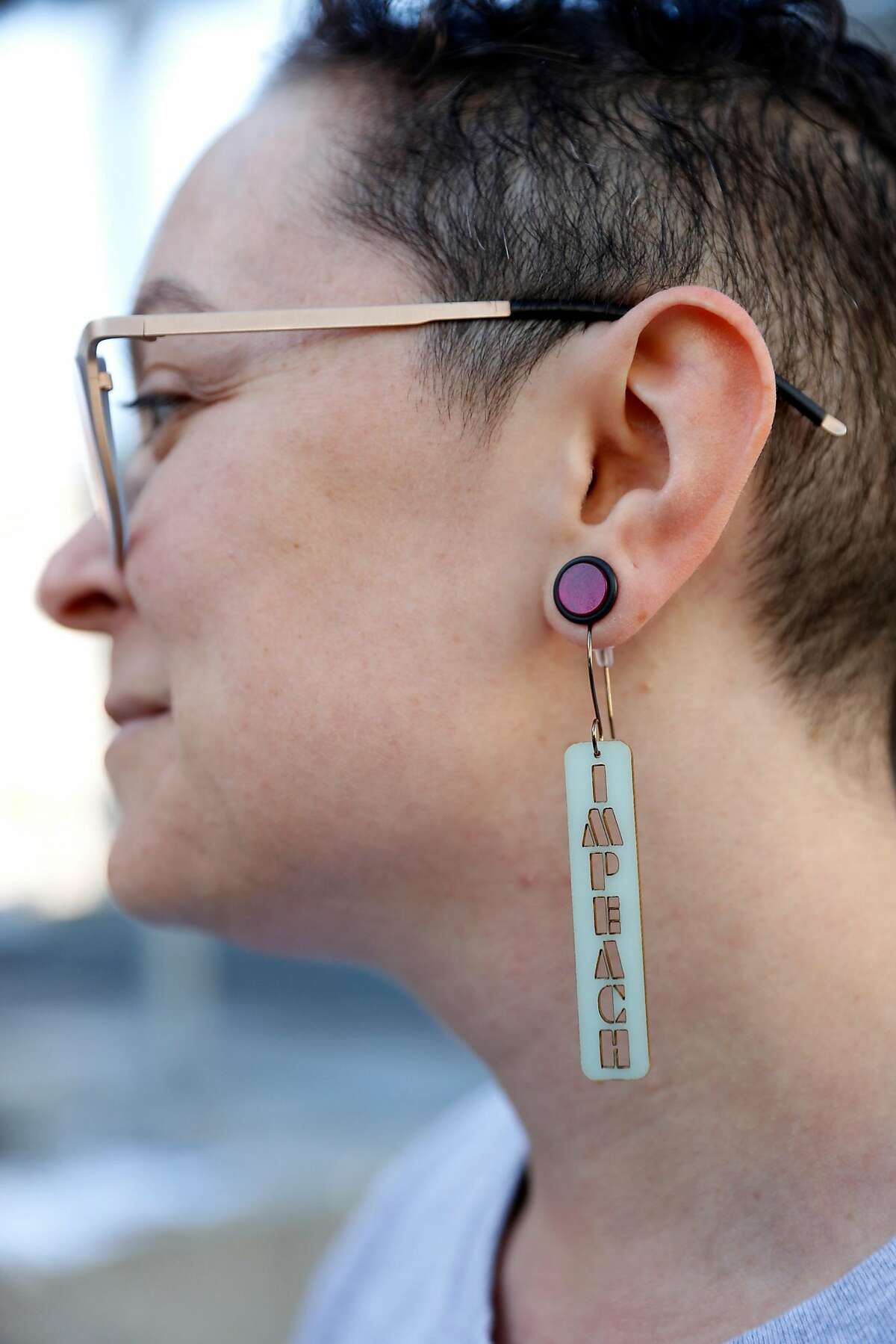 By the People's Mara Schechter wears Impeach earrings as activists hold an Impeach Donald Trump rally at 7th and Mission Streets outside of US Speaker of the House Nacy Pelosi's office in San Francisco, Calif., on Monday, April 22, 2019.