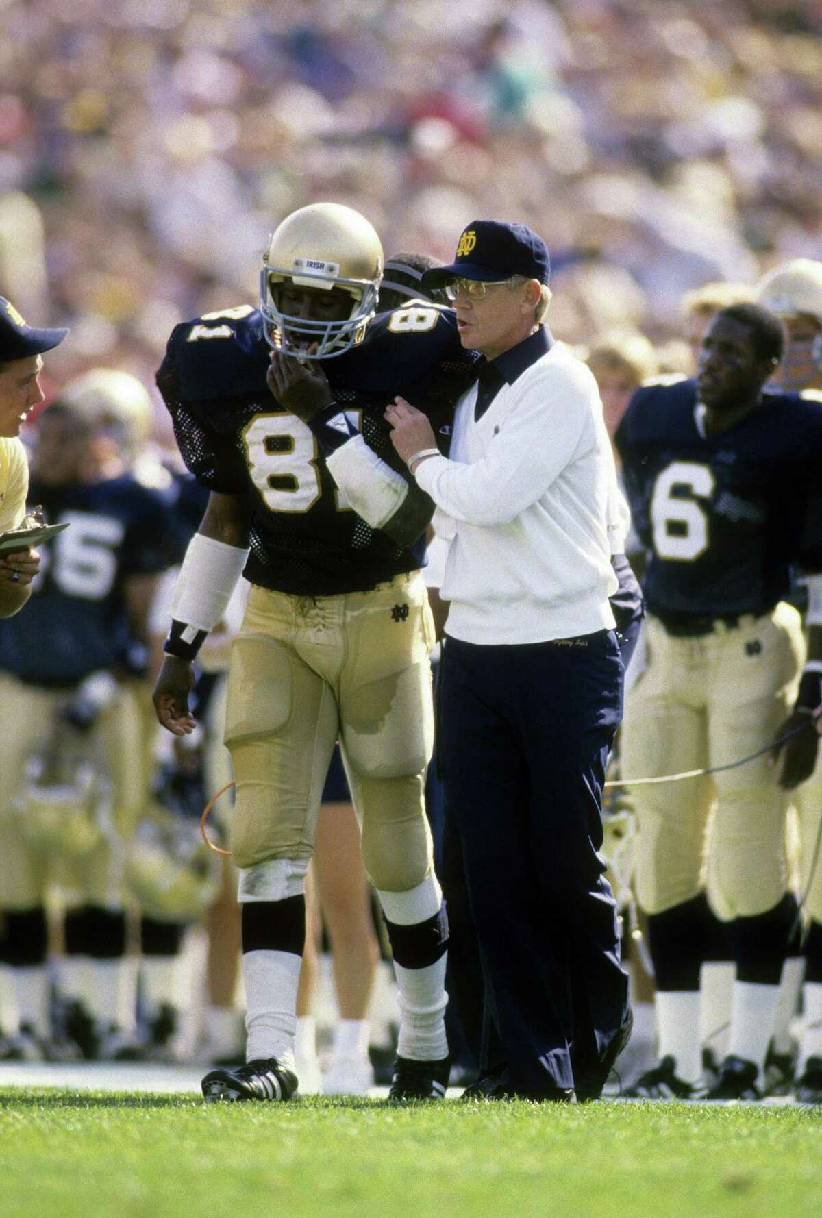 Head Coach Lou Holtz of the Notre Dame Fighting Irish (r) sends in a play with wide receiver Tim Brown #81 during an NCAA football game against the University of Michigan September 10, 1988 at Notre Dame Stadium in South Bend, Indiana. Holtz coached the Notre Dame Fighting Irish from 1986-1996.