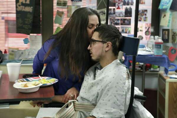 Kamini Del Barba leans over and kisses her son as he prepares to leave for physical therapy.