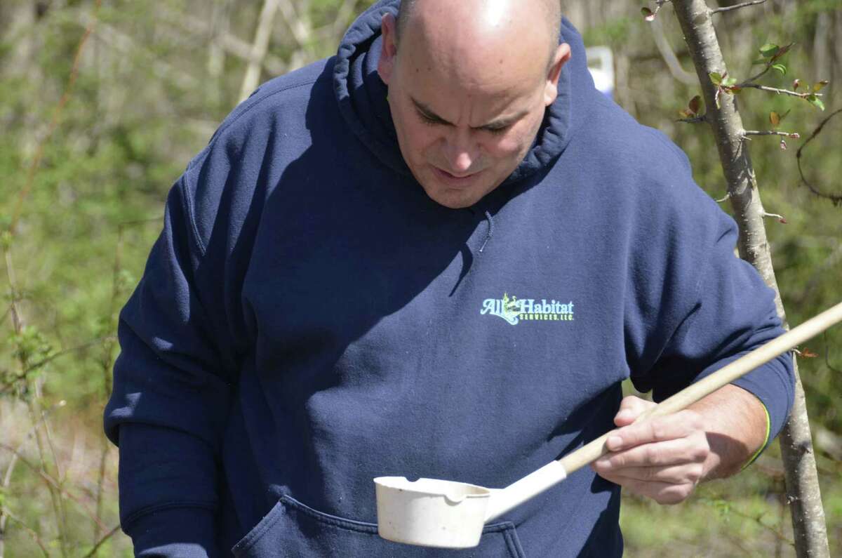 David Roach from All Habitat Services looks at a collection of water in a cup to see if he can spot mosquito larvae during a mosquito control demonstration in Milford, Conn. April 23.