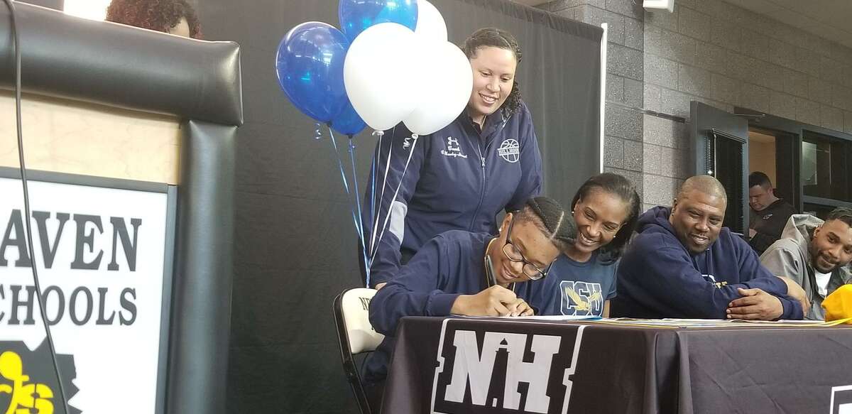 Hillhouse’s Tyree Allen, far left, signs a national letter of intent to play basketball at Coppin State. Looking on are Hillhouse coach Catrina Hawley-Stewart (behind), mom Stacey Allen, stepfather Maurice Williamson and older brother Tavon.