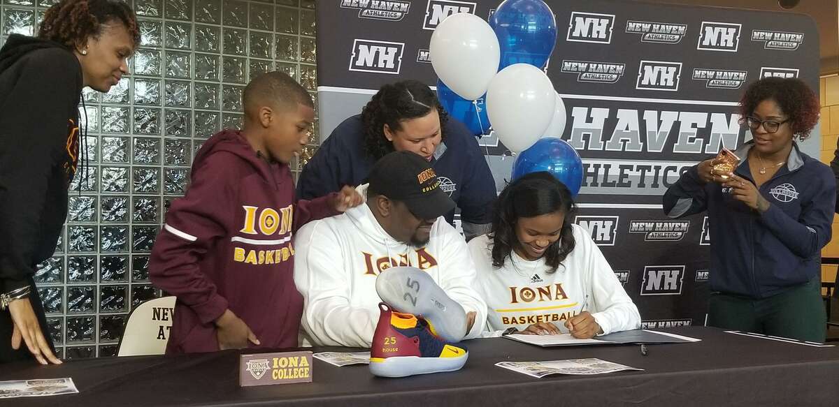 Hillhouse’s Tanayja London, second from right, signs a national letter of intent to play basketball at Iona College. Looking on are, from left: her mom Chastity, brother Jordan, father Rich, Hillhouse coach Catrina Hawley-Stewart and Hillhosue assistant Chanel Rice.