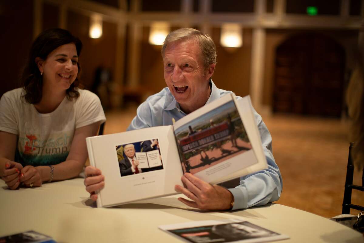 Tom Steyer laughs at a photo in a book given to him by Lynn Larocca, left, of the Alameda for Impeachment group on Tuesday, April 23, 2019, in Pleasanton, CA.