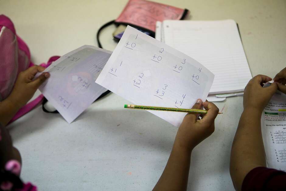 A participant in an after-school program holds up arithmetic flashcards during the after-school program.