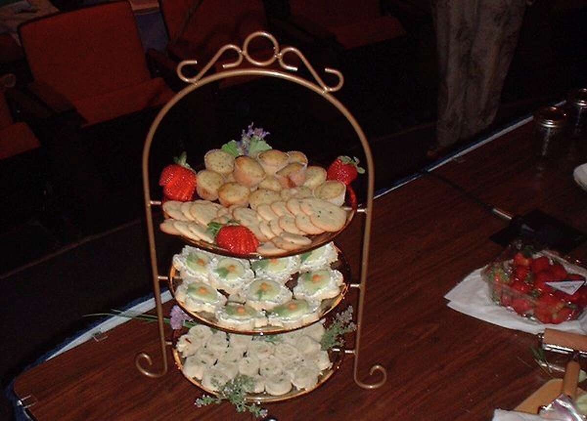 Cucumber sandwiches featuring herbed cheese are shown on the middle tier of a display rack.