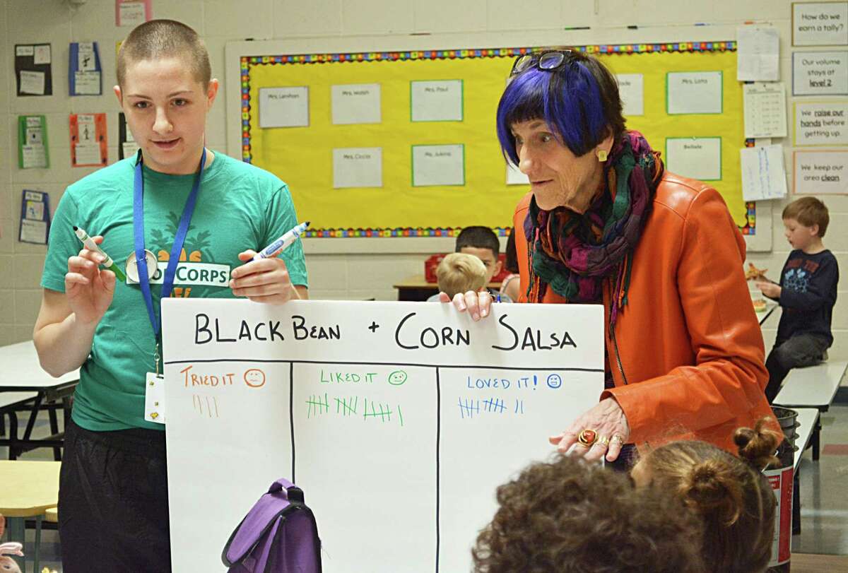 Paige Petit, FoodCorps AmeriCorps service member, left; and U.S. Rep. Rosa DeLauro, D-3, poll Macdonough Elementary School first- and fourth-grade students Wednesday in the cafeteria to learn if they liked sampling black bean and corn salsa.