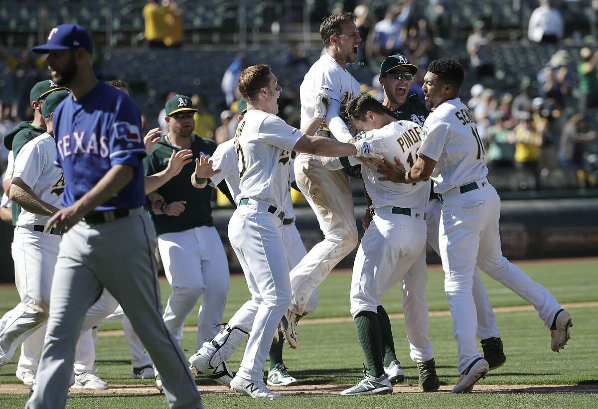 Oakland Athletics' Chad Pinder, second from right, is congratulated by teammates after driving in the winning run against the Texas Rangers during the ninth inning of a baseball game in Oakland, Calif., Wednesday, April 24, 2019. (AP Photo/Jeff Chiu)