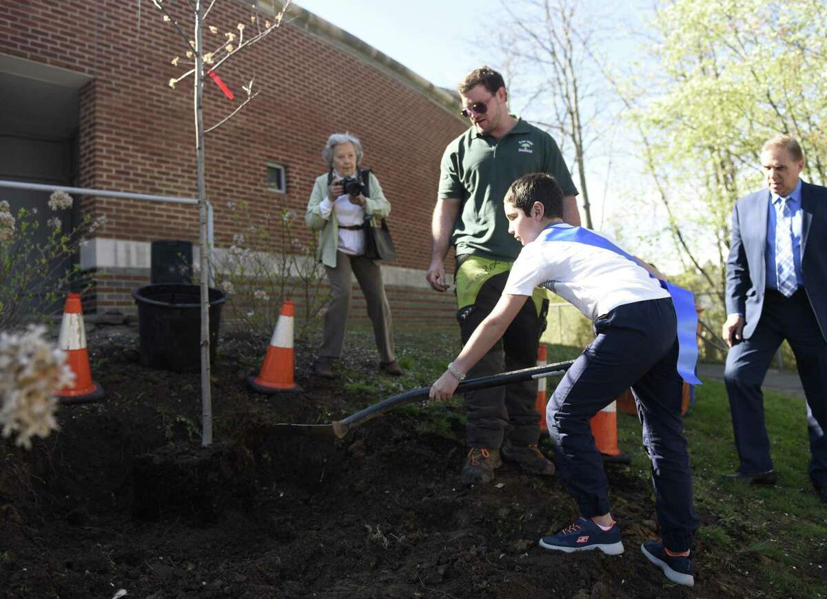 Fifth-grader Toby Gomez heaves a pile of dirt at the base of a newly-planted tree at the Arbor Day tree-planting at Cos Cob School in the Cos Cob section of Greenwich, Conn. Thursday, April 25, 2019. Representatives from DEEP and the Greenwich Tree Conservancy joined Cos Cob students and faculty to plant a tree behind the school as students sang "This Land Is Your Land."