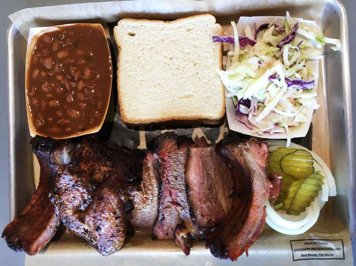 A three-meat barbecue plate from Brickyard BBQ that includes baby back ribs, smoked chicken, brisket, baked beans and coleslaw.