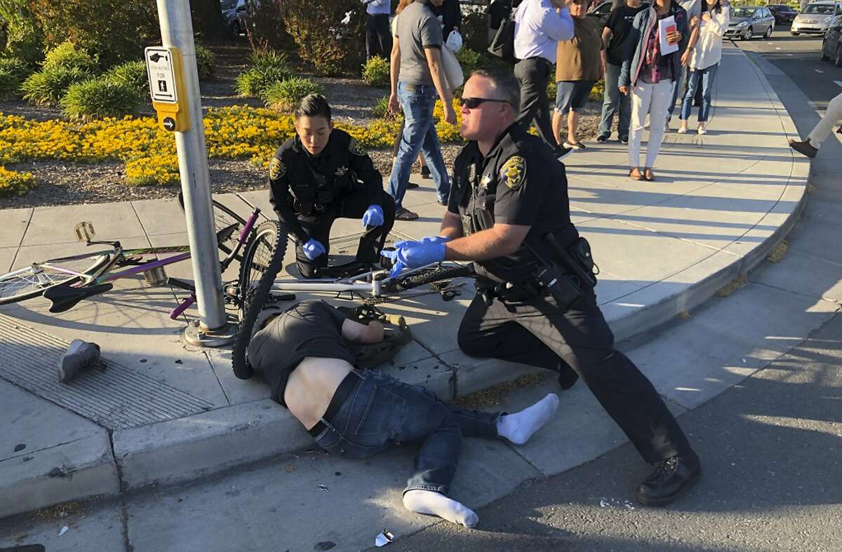 In this photo taken Tuesday, April 23, 2019, provided by Don Draper, a victim of a car crash is offered assistance from police in Sunnyvale, Calif. Draper, a witness to the crash that injured several people, said he was waiting for the light to turn green when a Toyota Corolla plowed through the intersection at high speed. (Don Draper via AP)