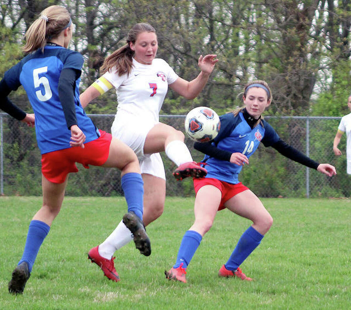 Roxana’s Kortni Laws (7) tries to control the ball between Carlinville’s Adrienne Welte (5) and Rory Drew 914) during Thursday’s South Central Conference game in Carlinville. The Cavies won 3-1.