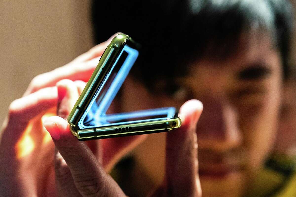 An attendee holds a Samsung Electronics Co. Galaxy Fold mobile device during an unveiling event in New York, U.S., on Monday, April 15, 2019. Samsung originally announced the phone in February and said it goes on sale April 26 at the wallet-stretching price of $1,980. But technical glitches have postponed its launch.