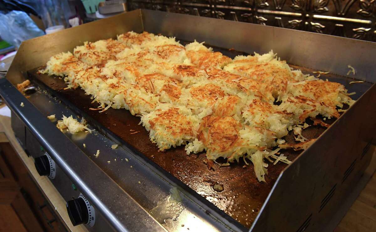 Hash browns cook on an industrial sized stove.