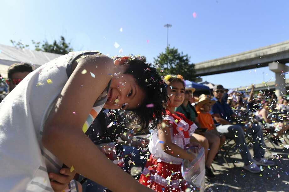 Noah McAtee, 9, shakes confetti from his hair as Madison Flores, 4, prepares to toss more during the Battle of Flowers Parade along Broadway on Friday, April 26, 2019. Photo: Billy Calzada/Staff Photographer
