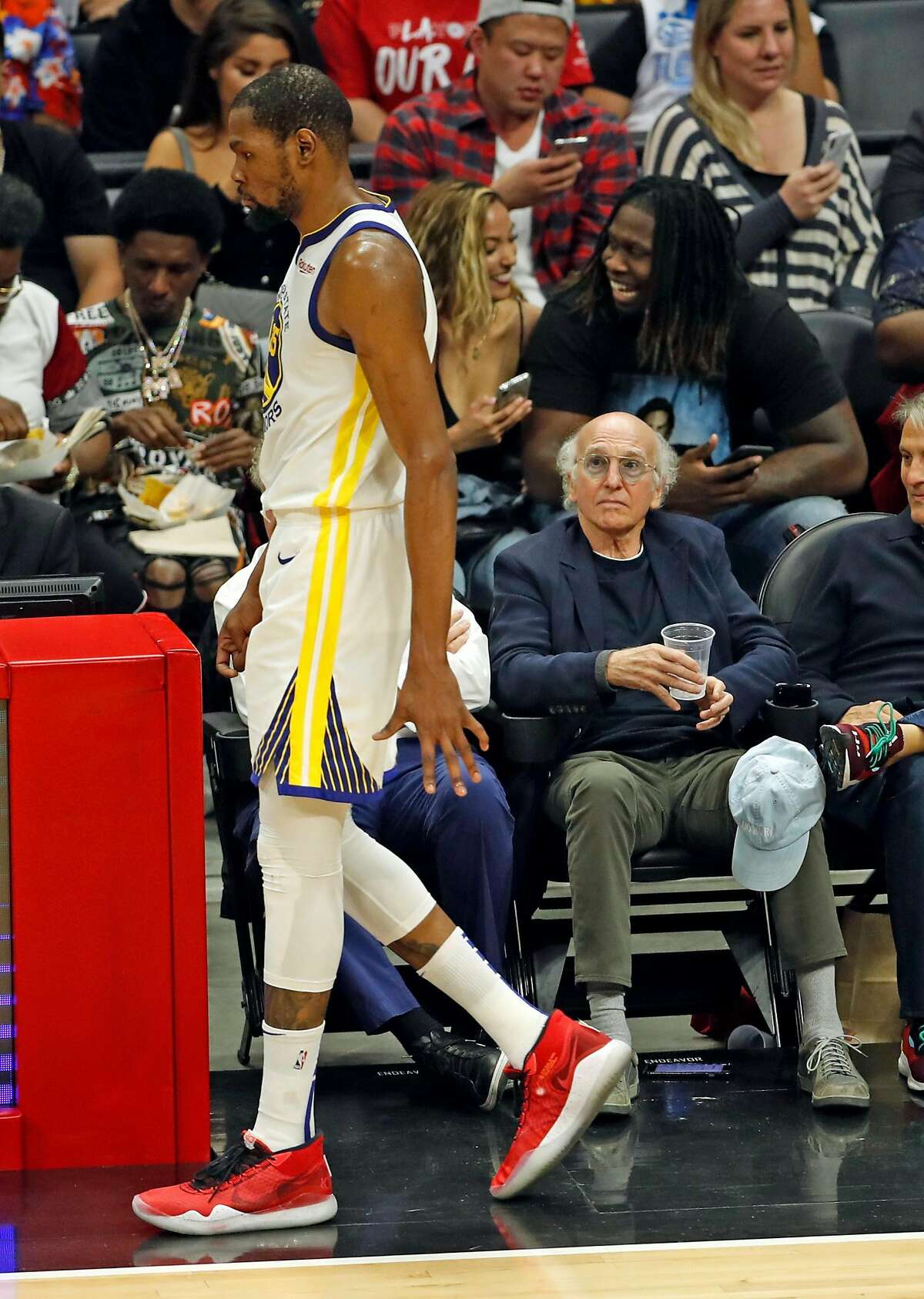 Larry David watches Golden State Warriors' Kevin Durant walk past in 3rd quarter against Los Angeles Clippers during Game 6 of NBA Western Conference first round playoffs at Staples Center in Los Angeles, Calif., on Friday, April 26, 2019.
