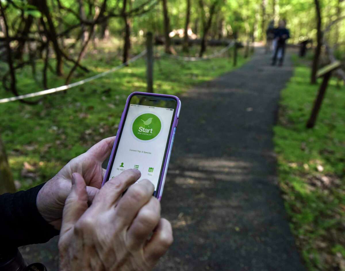 A birdwatcher launches the eBird app to record her sightings at the District of Columbia's Rock Creek Park. With the app, Cornell Lab collects millions of sightings.