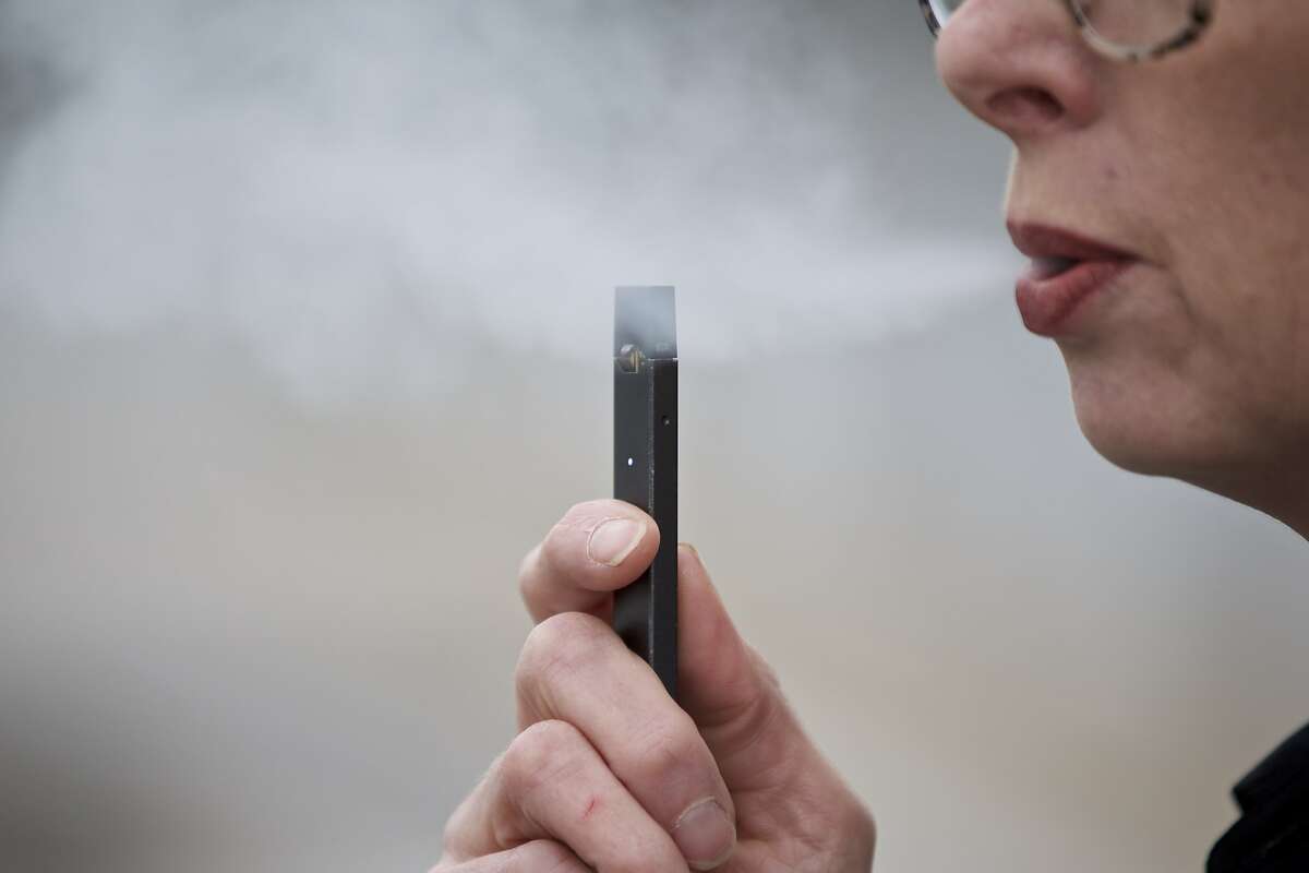 Chantel Williams exhales a puff of vapor from a Juul pen in Vancouver, Wash., Tuesday, April 16, 2019. Britain and other nations have had success promoting e-cigarettes as a lower-risk alternative to smokers, without seeing a surge in underage vaping. But they also have tighter regulations, including strict limits on advertising. (AP Photo/Craig Mitchelldyer)
