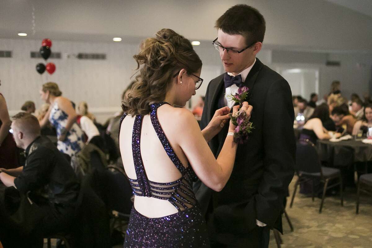 Coleman High School senior Bailey Ranck, left, fixes the bouttonniere of junior Kyle Nohel, right, during Coleman's prom at PohlCat Golf Course in Mount Pleasant on Saturday, April 27, 2019. (Katy Kildee/kkildee@mdn.net)