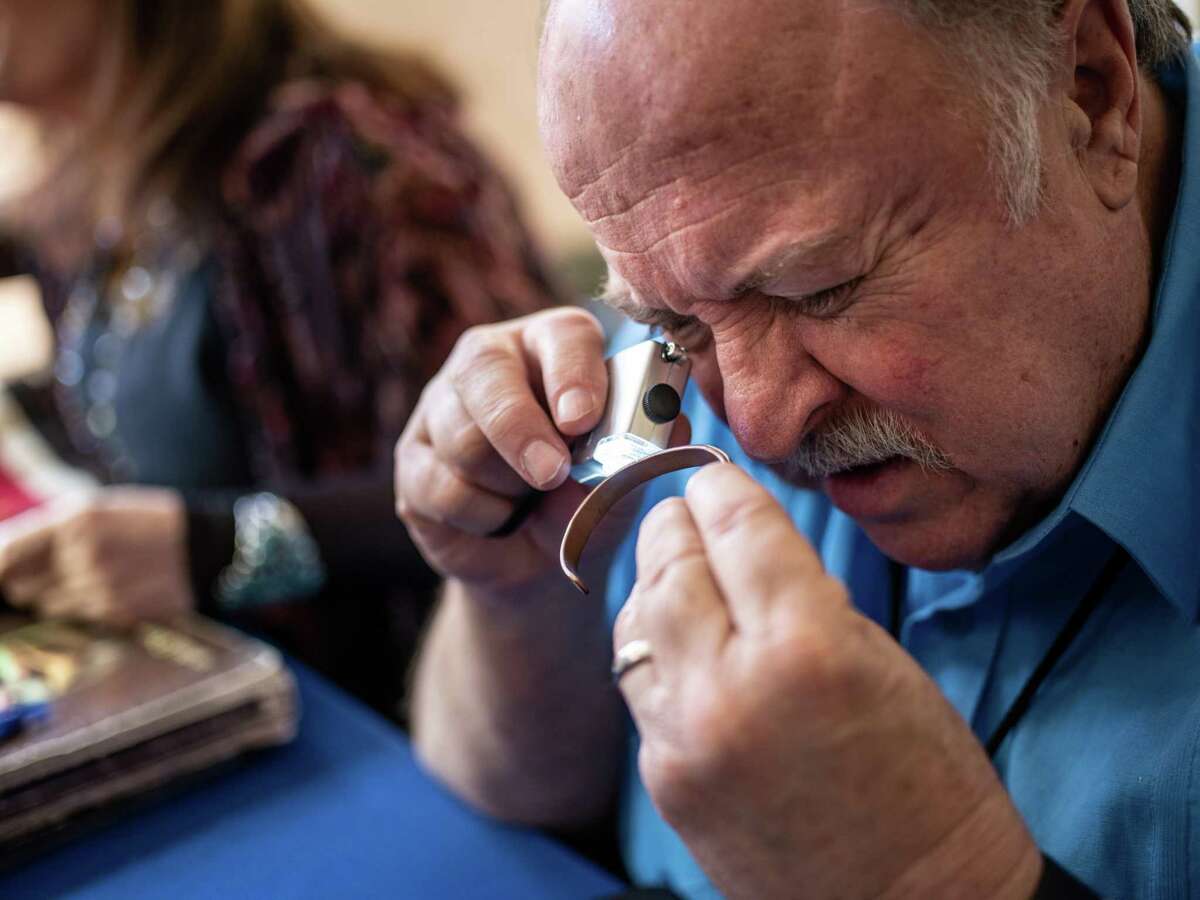 Bruce Shackelford, an appraiser of “Tribal Arts,” looks at a copper, Navajo bracelet during a taping of the PBS television series, “Antiques Roadshow,” at the McNay Art Museum.