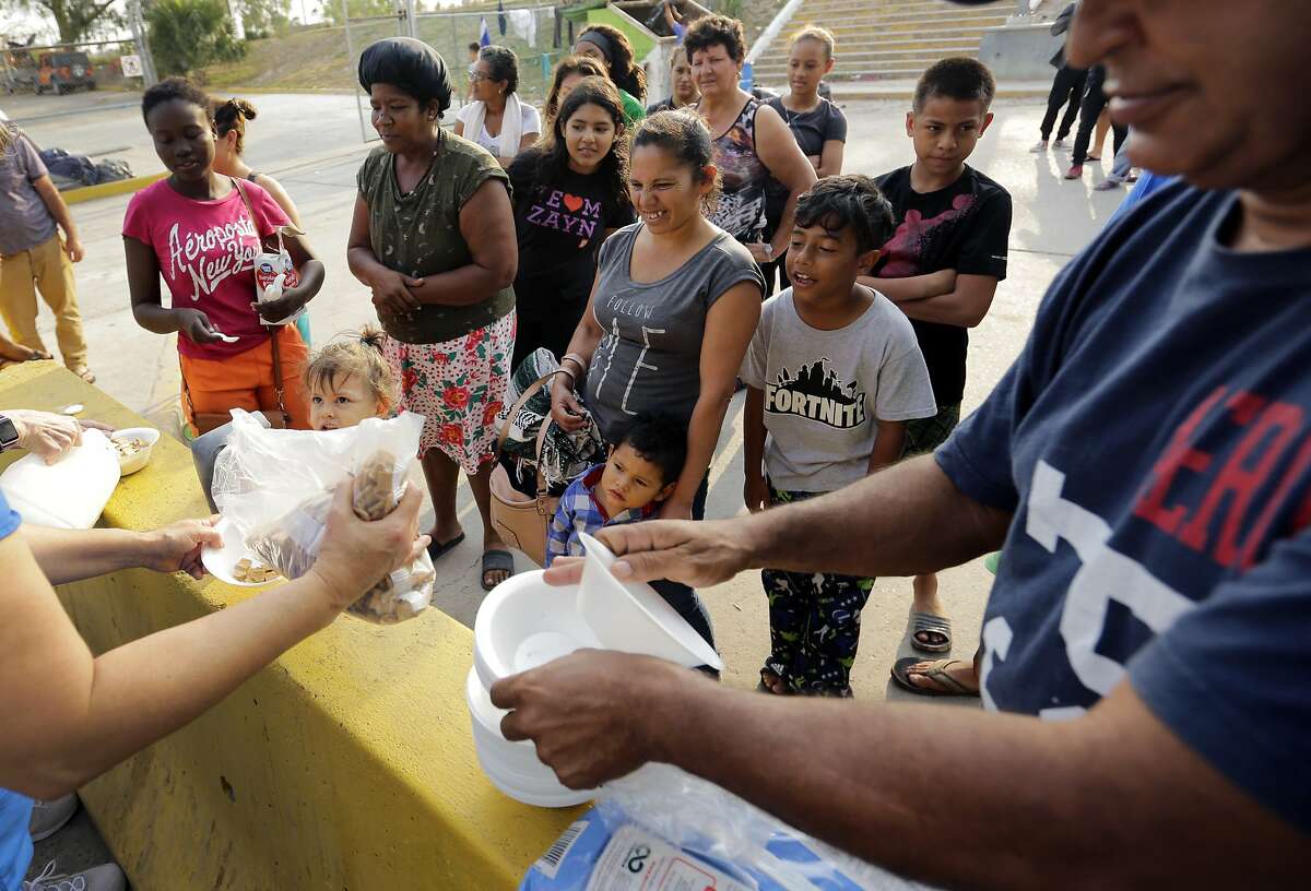Migrants seeking asylum in the United States receive breakfast from a group of volunteers in near the international bridge, Tuesday, April 30, 2019, in Matamoros, Mexico. President Donald Trump is proposing charging asylum seekers a fee to process their applications as he continues to try to crack down on the surge of Central American migrants seeking to cross into the U.S. (AP Photo/Eric Gay)