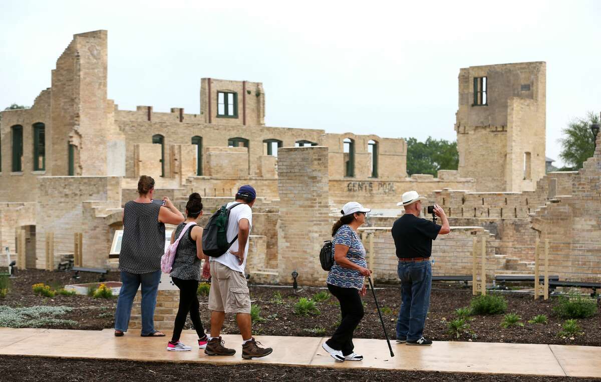 People walk Tuesday, April 30, 2019 past the former Hot Wells Hotel during the grand opening of the Hot Wells of Bexar County park. The once-crumbling building has been stabilized by Bexar County as part of turning the approximately four acre site into a park which is connected to the Mission Reach section of the San Antonio River Walk.