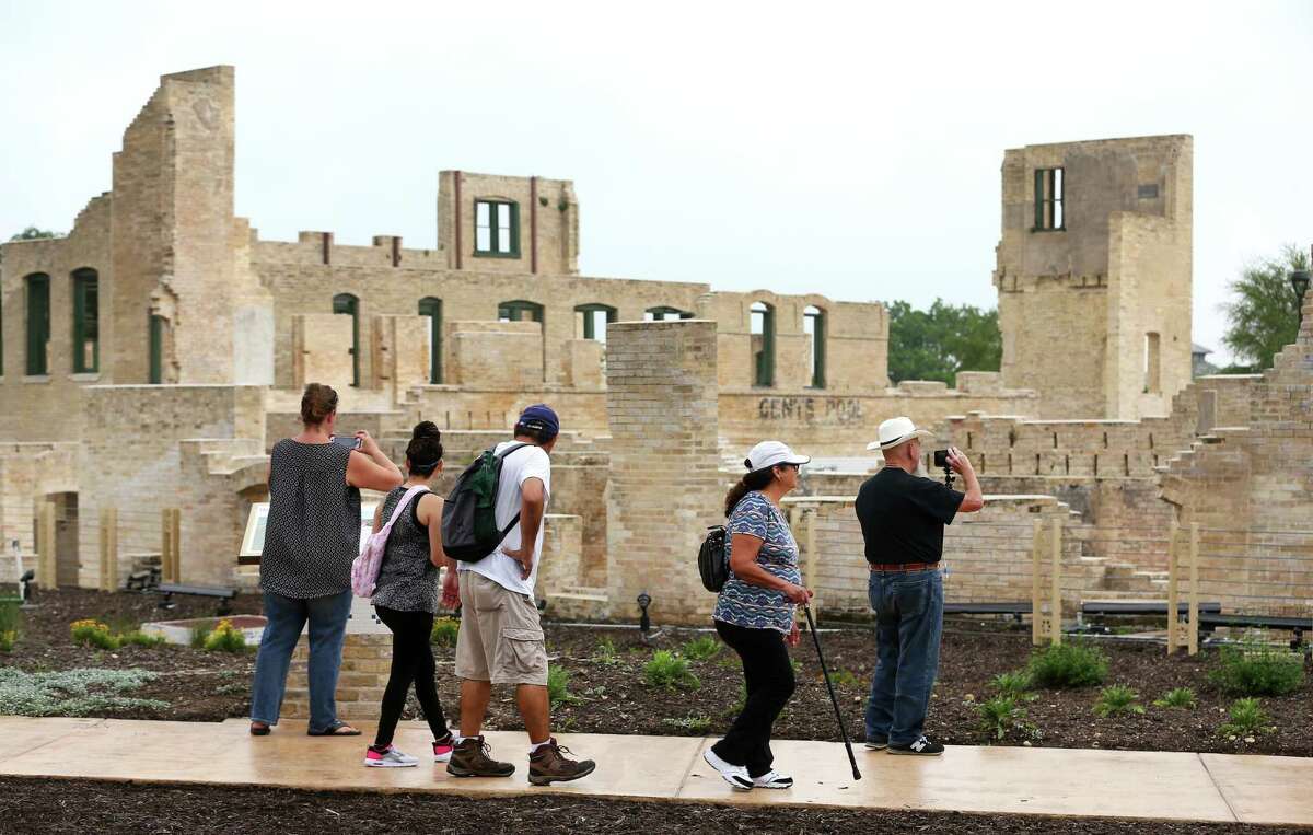 People walk past the former Hot Wells Hotel during the grand opening of the Hot Wells of Bexar County Park last year. The county stabilized the once-crumbling building while turning the 4-acre site into a park connected to the Mission Reach section of the San Antonio Riverwalk.
