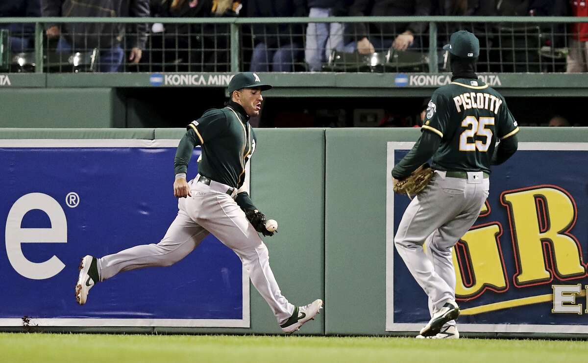 Oakland Athletics center fielder Ramon Laureano, left, drops a drive by Boston Red Sox's J.D. Martinez during the fifth inning of a baseball game at Fenway Park, Tuesday, April 30, 2019, in Boston. Laureano was charged with an error on the play. At right is Oakland Athletics right fielder Stephen Piscotty. (AP Photo/Charles Krupa)