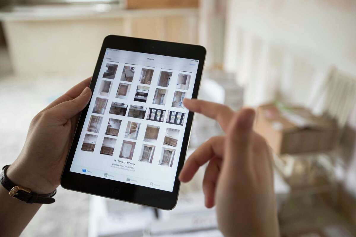 Bailee Wright, transaction coordinator for Entera, scrolls through photos she took of progress on a home remodel for an institutional investor on Friday, March 8, 2019, in Houston.