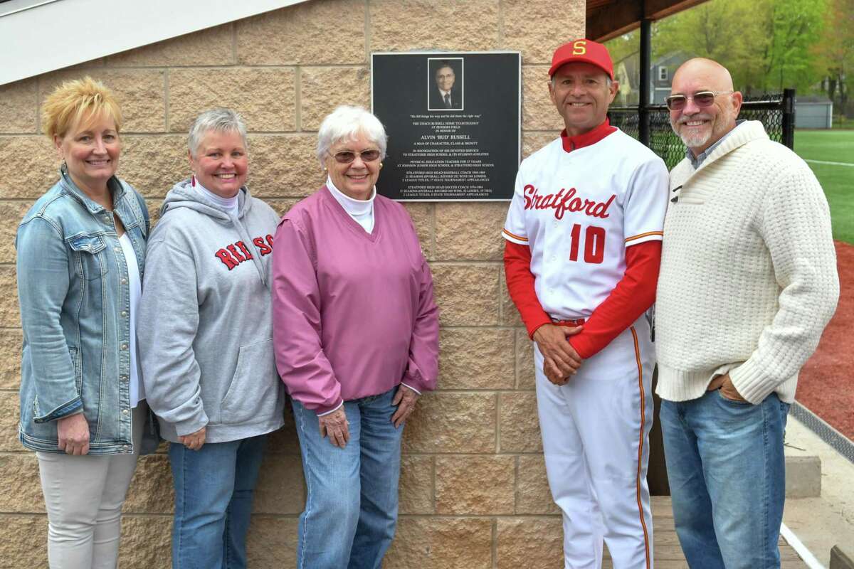Head Coach Mick Buckmir of the Stratford Red Devils stands with the Russell Family and plaque as the Home Team Dugout is dedicated to former coach Alvin "Bud" Russell prior to a game against the Immaculate Mustangs on Wednesday May 1, 2019 at Penders Field in Stratford, Connecticut.
