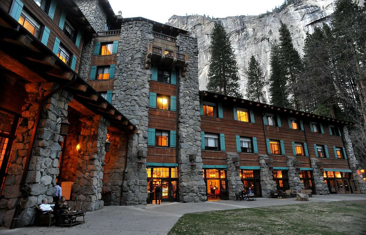 In this March 24, 2014 file photo, the historic Ahwahnee Hotel is lit up as dusk falls over Yosemite Valley, in Yosemite, Calif. The names of iconic hotels and other facilities in the world-famous Yosemite National Park change back after battle over who owns the intellectual property.