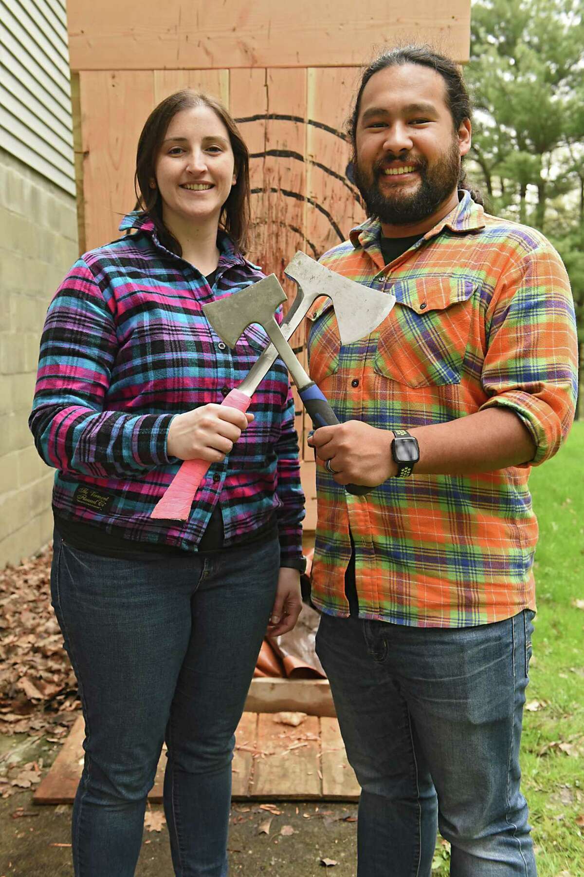 Kristyn Muller and Mark Mirasol, the founders of Lazy Axe, hold axes in front of a target in the back of their home on Friday, May 3, 2019 in Rensselaer, N.Y. The couple hopes to open their business, which is on Central Ave. in Colonie, in a month.(Lori Van Buren/Times Union)
