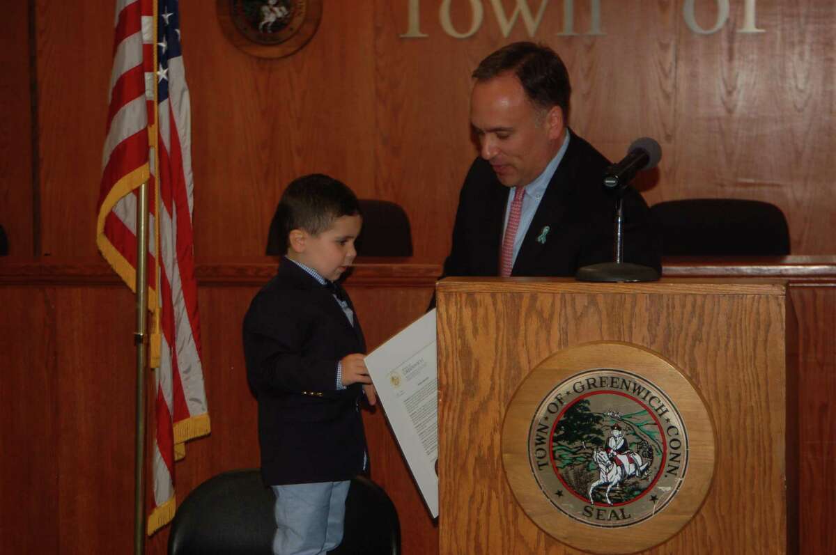 First Selectman Peter Tesei presents a proclamation to Colton Zagger, the son of MAT co-founder Kaile Zagger and the grandson of Marilyn Ann Trahan, whose fight against ovarian cancer inspired the effort.