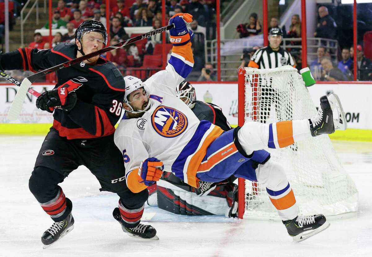 Carolina Hurricanes' Patrick Brown (36) takes a stick to the face while chasing the puck with New York Islanders' Cal Clutterbuck (15) during the second period of Game 3 of an NHL hockey second-round playoff series in Raleigh, N.C., Wednesday, May 1, 2019. (AP Photo/Gerry Broome)