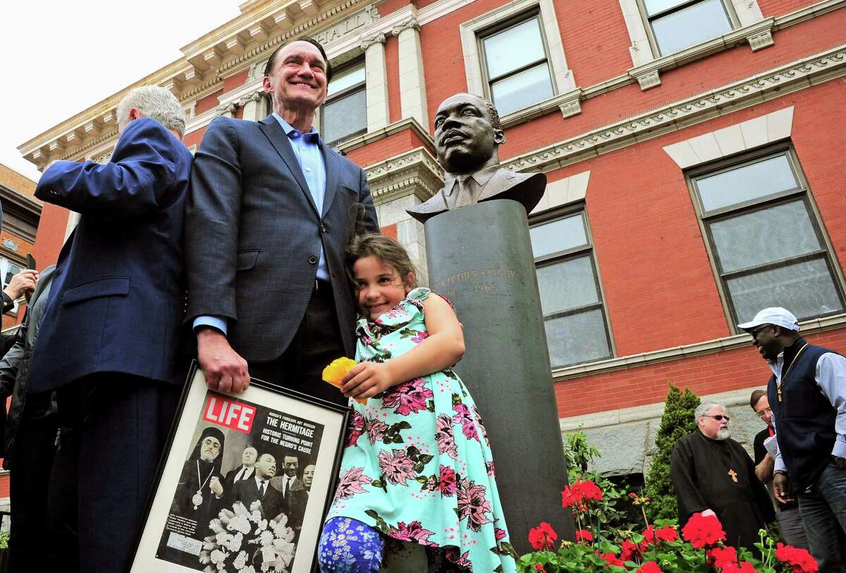 Greg Stamos holds a framed Life magazine cover as he stands with his granddaughter Parela, 7, in front of the bust of Martin Luther King Jr. that was unveiled in front of Ansonia City Hall in Ansonia, Conn., on Saturday May 4, 2019.