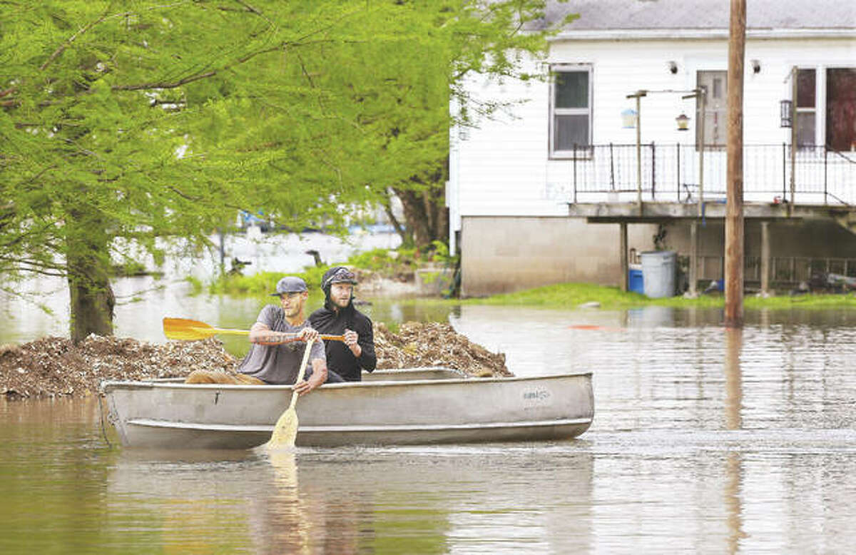 Two men paddle their way through Grafton Monday where high water and docked john boats seemed to be everywhere.