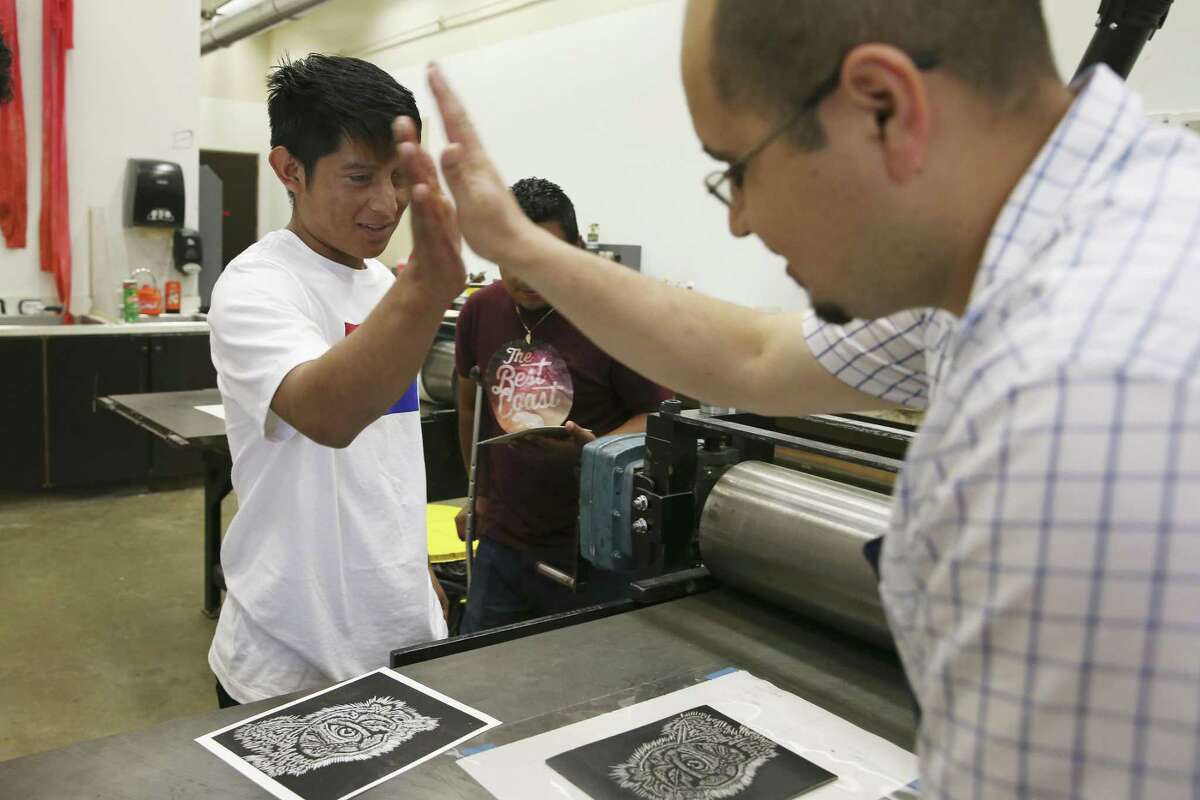 Walter Rodriguez, 18, left, high fives Juan de Dios Mora during a printmaking class at UTSA. Rodriguez titled his piece, “Sentimiento,” which means “Feeling” in English. In the center of the heart in his print is an eye. “The essential is invisible through the eye,” Rodriguez said of his print.